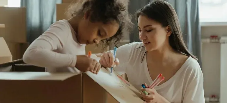Mother and daughter drawing on a cardboard box