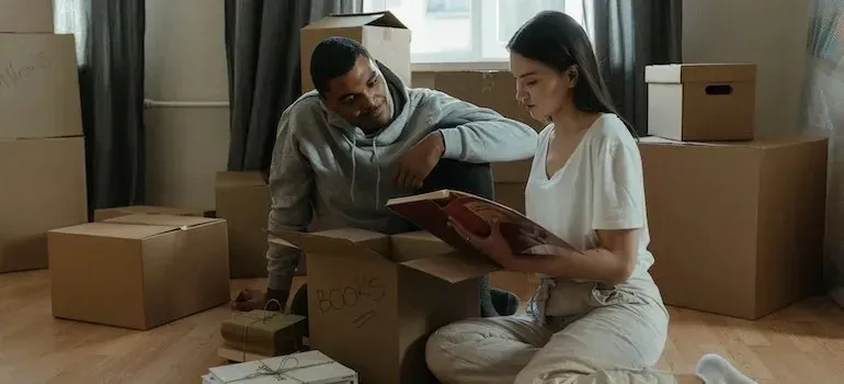 Couple unpacking box of books in new home