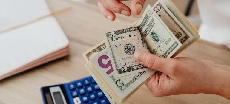 Hands counting cash over calculator