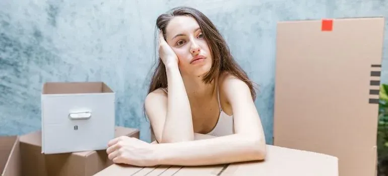 Tired woman leaning on moving boxes
