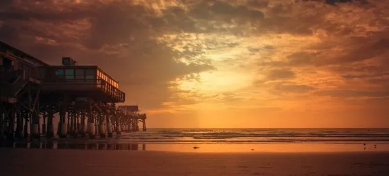 Ocean pier on sandy beach under golden sunset