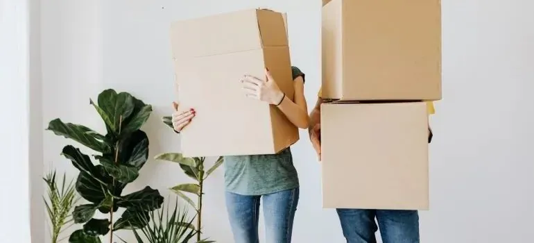 Two people carrying large boxes that hide their faces
