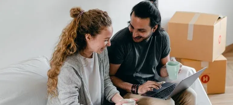Couple with laptop among moving boxes