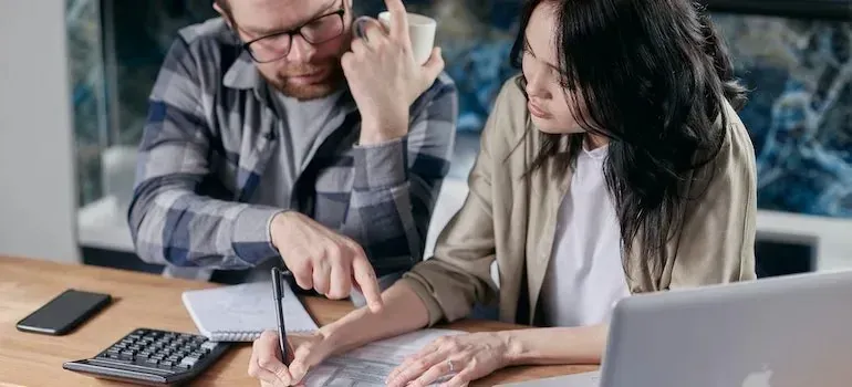 Couple reviewing documents with calculator and laptop at table