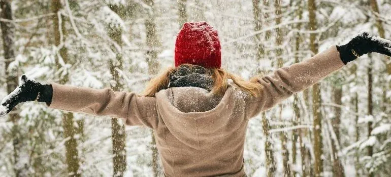 Woman in snowy forest, arms spread