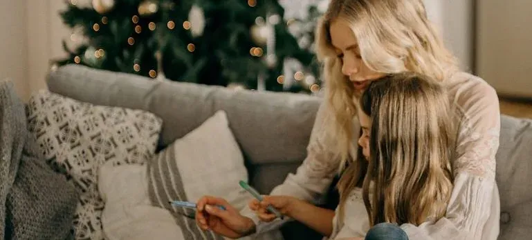 Mother and daughter on couch, Christmas tree