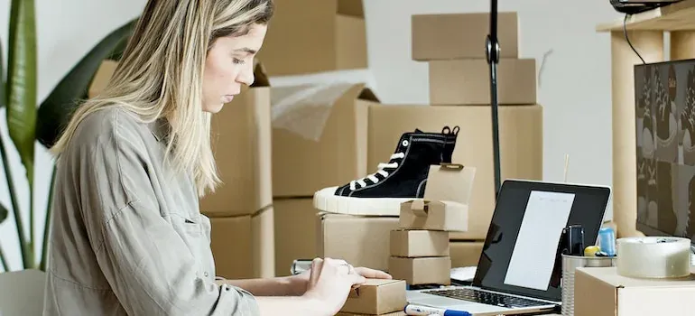 Woman packing shoes at laptop desk