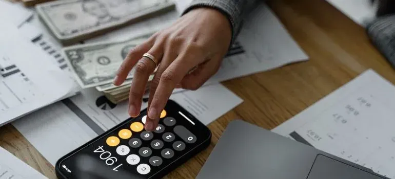 Hand using calculator with cash