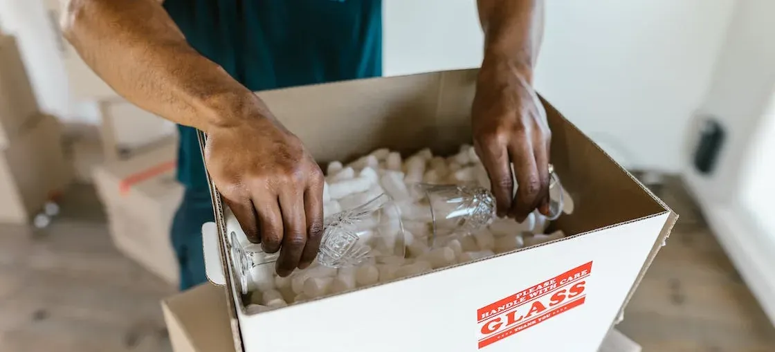 Packing glassware in box labeled GLASS