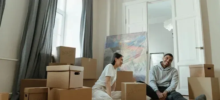 Couple laughing among boxes and a wrapped painting