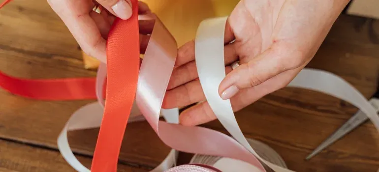 Hands holding satin ribbons on table