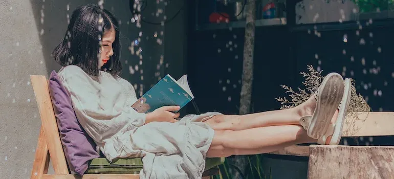 Woman reading book outdoors on chair
