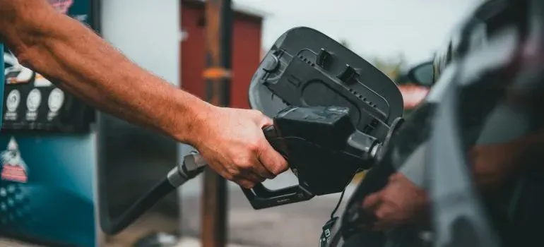 Hand pumping gas into car