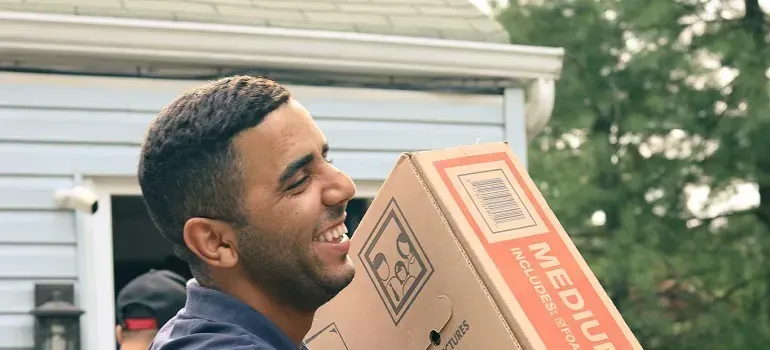Smiling mover carrying generic medium cardboard box