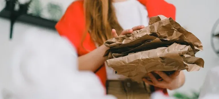 Woman holding crumpled brown packing paper