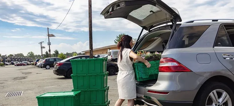 Woman loading green bins into SUV