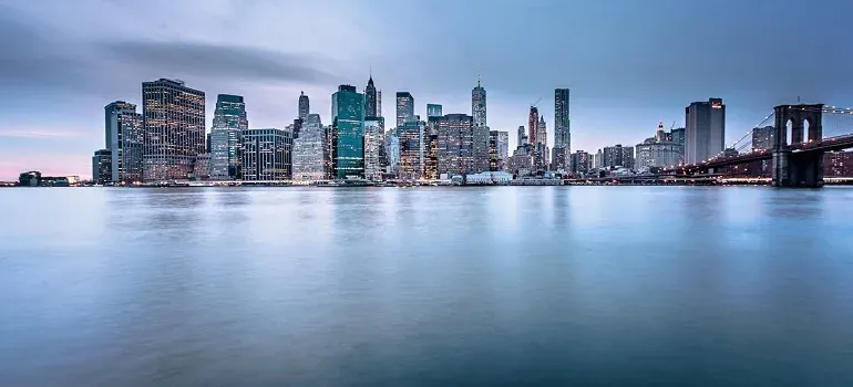 Manhattan skyline across water at dusk