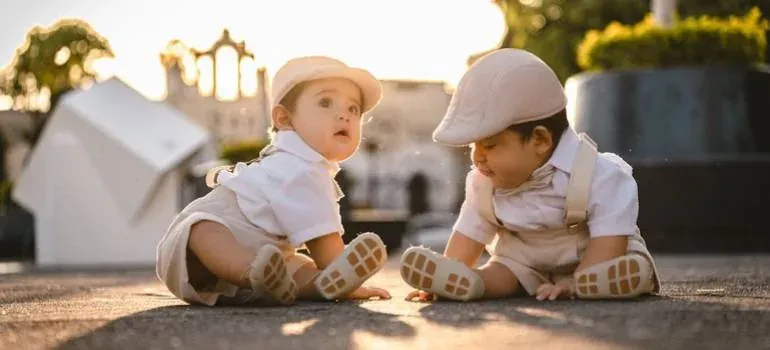 Two babies in caps sitting outdoors