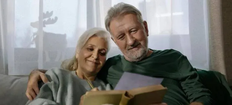 Senior couple reading book on sofa
