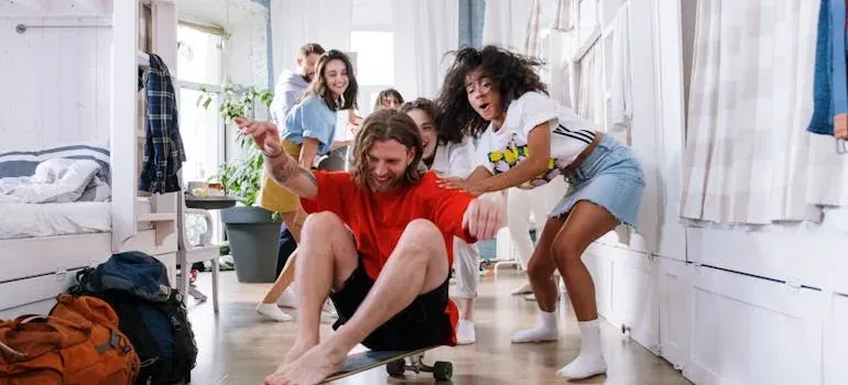 Friends pushing man on skateboard indoors
