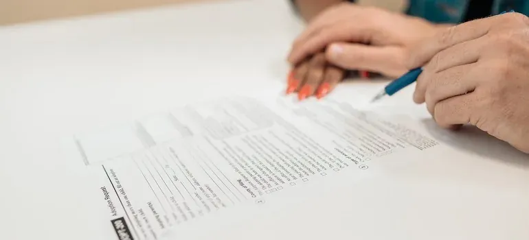 Hands filling out paper form with pen