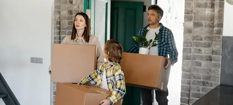 Family carrying boxes into new home