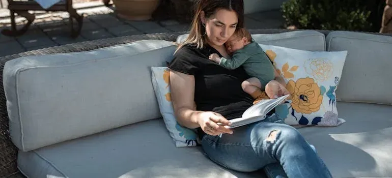 Mother reading book with baby on couch