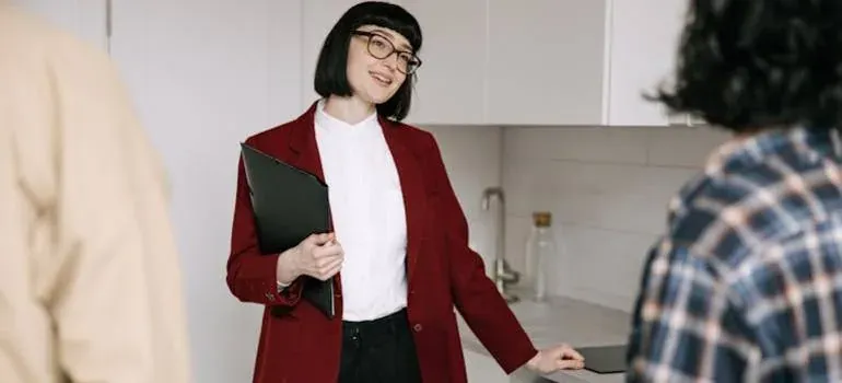 Agent with folder greeting couple indoors