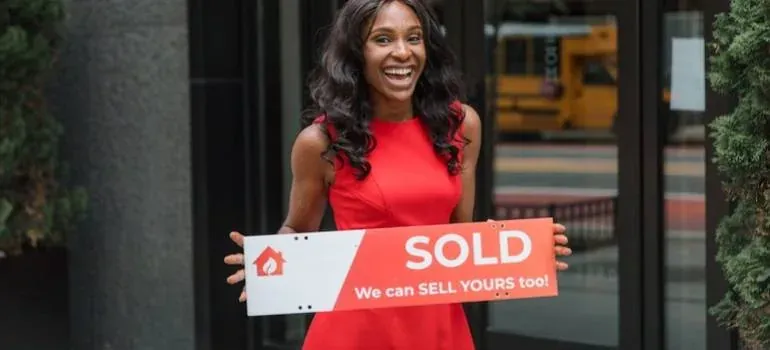 Woman in red dress holding SOLD sign