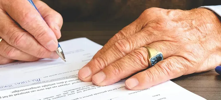Elderly hands signing document with pen