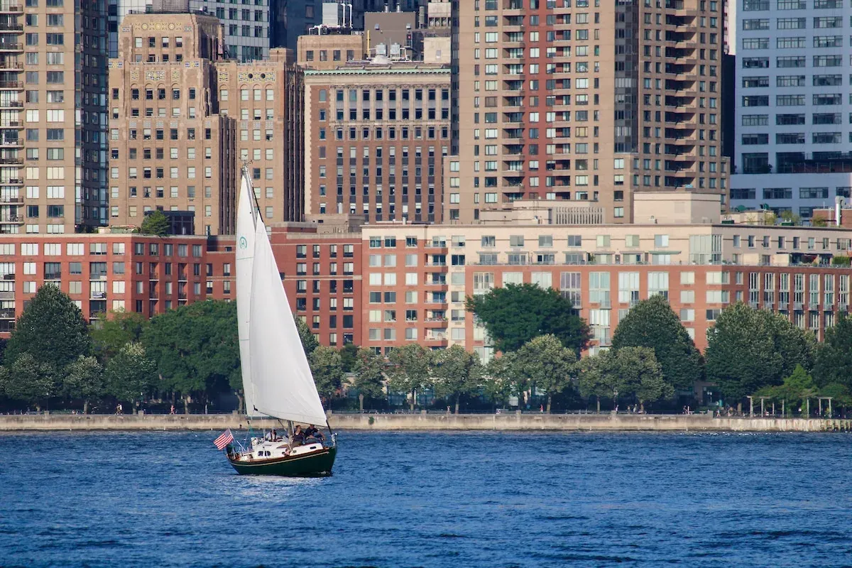 Sailboat on river before city buildings