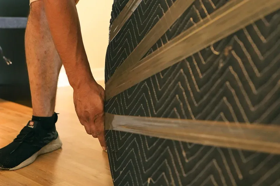 Movers wrapping a large mirror in protective packing material