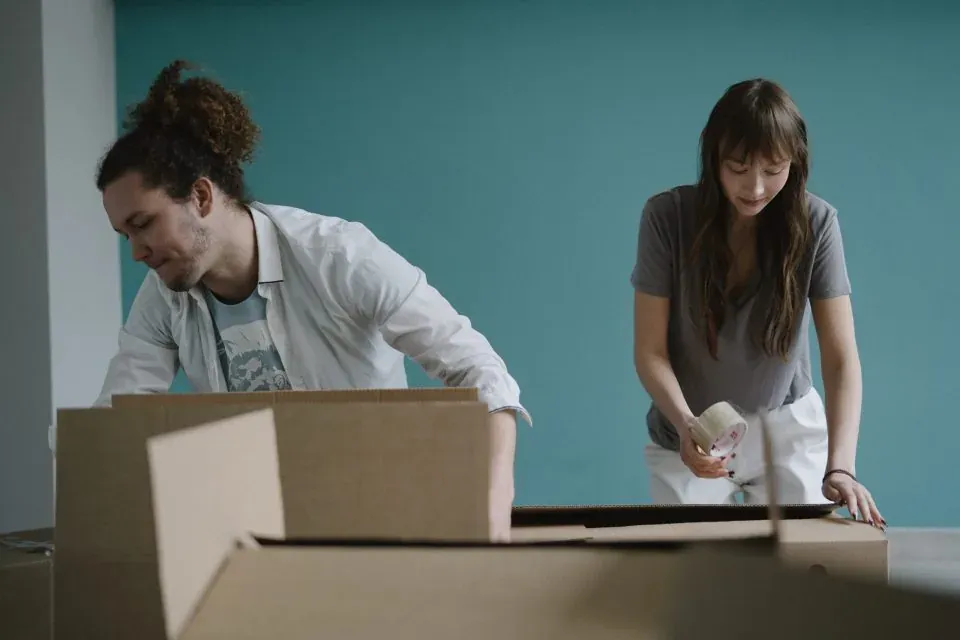 Person taping and labeling moving boxes in a New Jersey home
