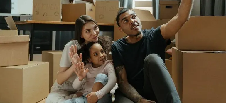 Family sitting among labeled moving boxes