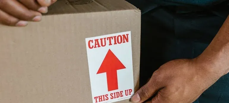Hands holding box with caution sticker