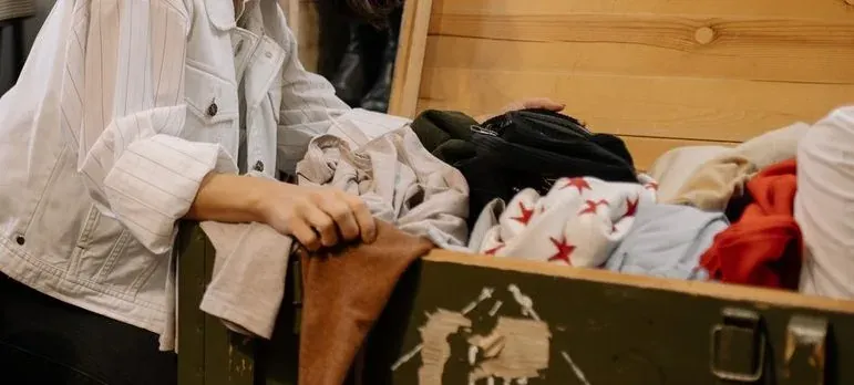 Woman packing clothes into green trunk
