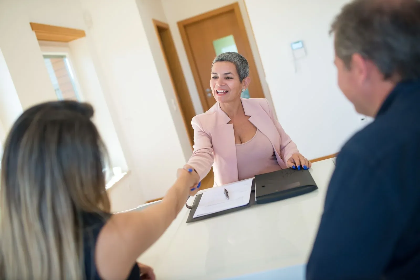A real estate agent shaking hands with happy clients after a home purchase